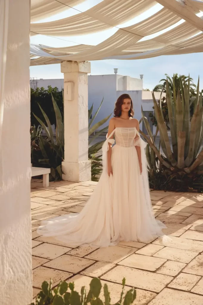 66400-Lillian West-Pure Bridal, Edmonton wedding dress, Edmonton  bridal shop, English net A-line gown with scoop neckline. Soft draping on bodice covers exposed boning detail. Back bodice is finished with covered buttons. Ethereal skirt flows into chapel length train. Pair with matching self-tie English net streamers sold separately as 66400SL